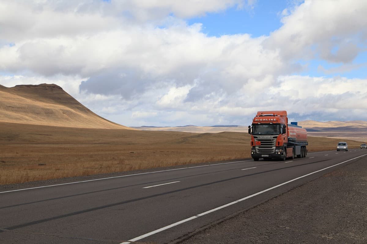 Semi-truck on a highway through rolling hills and open mountain country